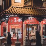 A vibrant night scene of lively Chinatown in London, featuring a traditional Chinese restaurant illuminated by red lanterns.